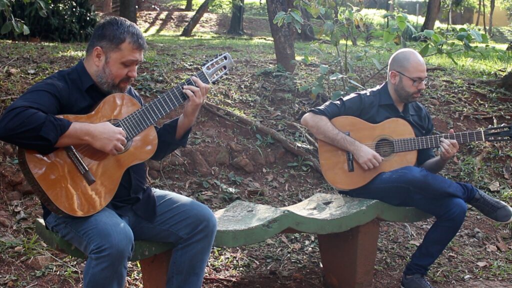2a foto do Duo Origens, composto por Guilherme Mauad tocando violão de 6 cordas e Henrique Candido Tocando Violão de 7 cordas sentados em uma praça